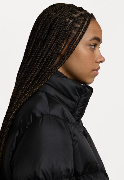 Black puffer jacket with a high collar, featuring quilted sections and a smooth texture. Model has braided hair styled down.