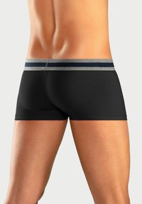 Boxer da uomo neri con una vita a righe grigie e blu navy, design aderente, superficie liscia e lunghezza a metà coscia, mostrando una vista posteriore.