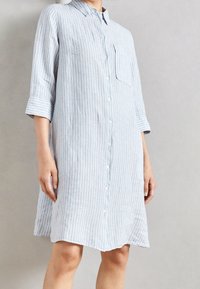 Lichtblauwe gestreepte shirtjurk met een kraag, driekwart mouwen, een knoopsluiting aan de voorkant en een zak aan de linkerkant.