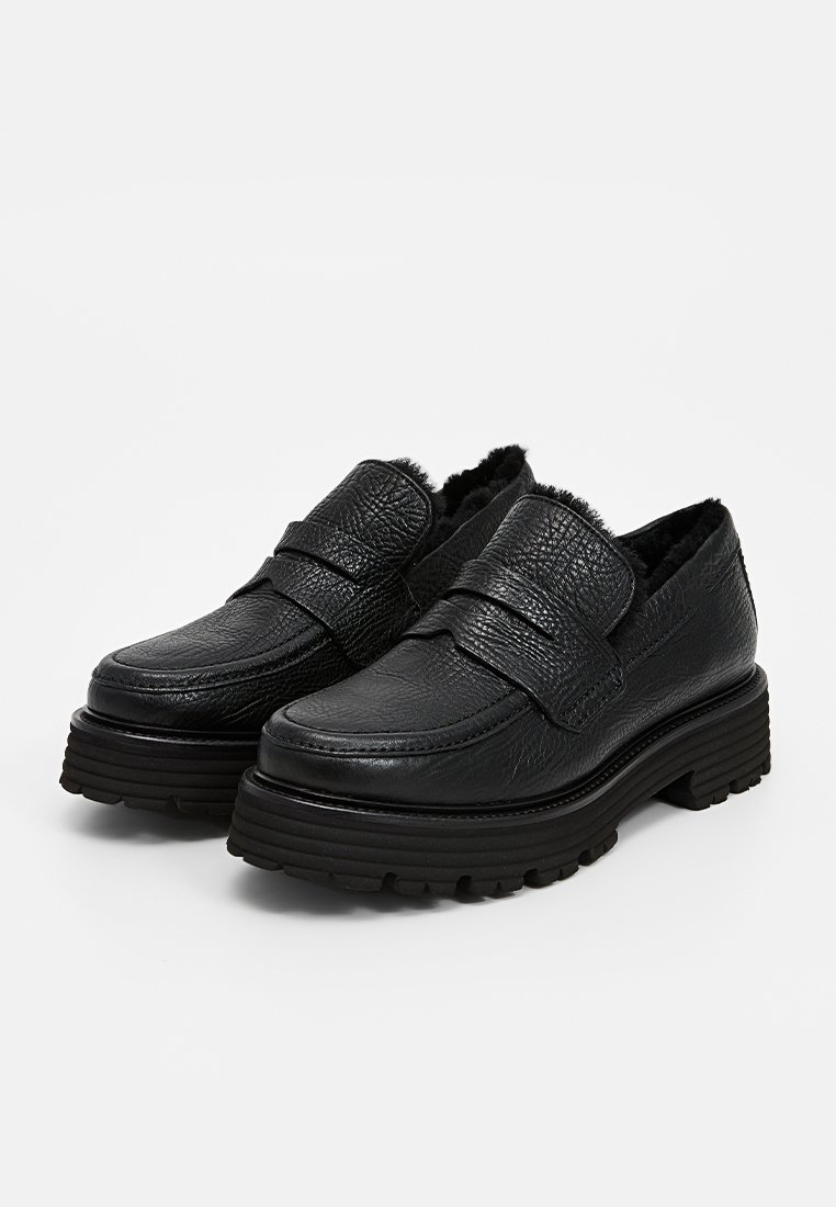 Schwarze Leder Slipper mit strukturierter Oberfläche, ausgestattet mit einem gepolsterten Riemen, dicker Sohle und einem weichen Innenfutter. Ideal für Komfort und Unterstützung.