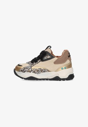 Sneaker beige scintillante con accenti dorati, lacci neri, materiali testurizzati e una suola chunky nera. Presenta dettagli blu e beige.