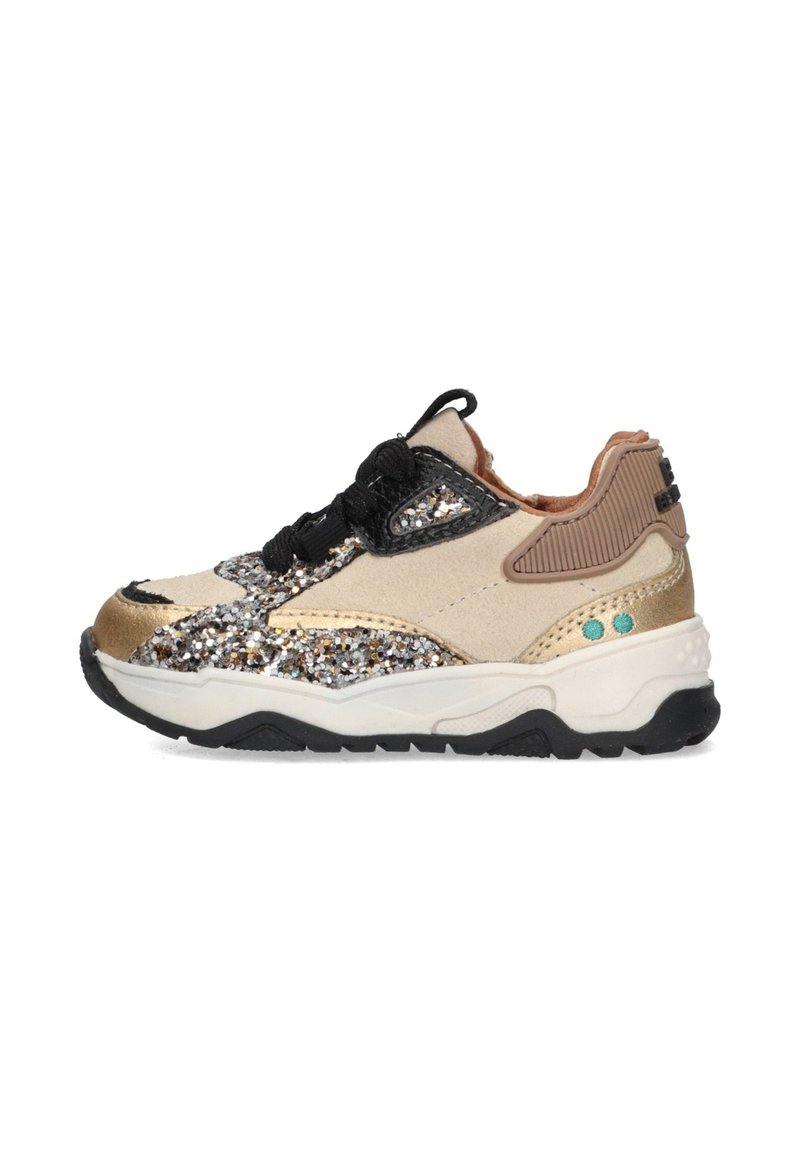 Zapatillas brillantes beige con acentos dorados, cordones negros, materiales texturizados y una suela negra gruesa. Presenta detalles en azul y tan.