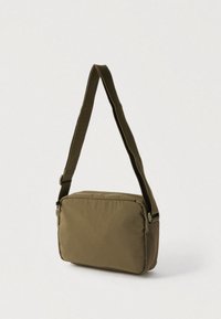 Ορθογώνια τσαντάκι χιαστί σε ελιά πράσινο χρώμα με ρυθμιζόμενο λουρί και φερμουάρ στην κορυφή, σε απλό φόντο.