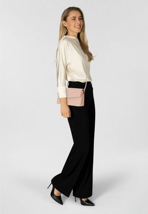 Schwarze, weit geschnittene Hosen, cremefarbene Bluse und eine hellrosa Umhängetasche. Schwarze spitze High Heels. Glatter Stoff und maßgeschneiderte Passform.