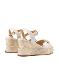 Sandali con zeppa bianchi con una piattaforma in paglia strutturata, dotati di chiusura a fibbia e cinturini in pelle liscia. Il design include dettagli incrociati.