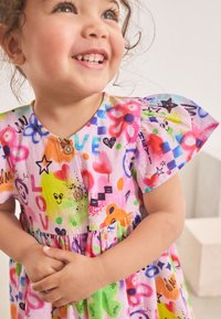 Vestito colorato in cotone con maniche corte a volant, caratterizzato da una combinazione di motivi e disegni in rosa, verde, giallo e blu. Bottoni in legno sul davanti.