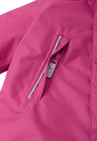 Różowa kurtka softshell z zamykaną kieszenią i srebrnym uchwytem. Materiał gładki, matowy z subtelną teksturą.
