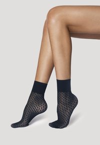 Sorte ankelstrømper lavet af gennemsigtigt netstof med ribbet kant. Designet har et åbent mønster og dækker foden og anklen.