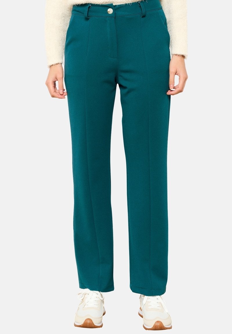 Pantalons teal taille haute avec une coupe droite, présentant une fermeture à un bouton, des plis sur le devant et des poches latérales. Portés avec des baskets blanches.