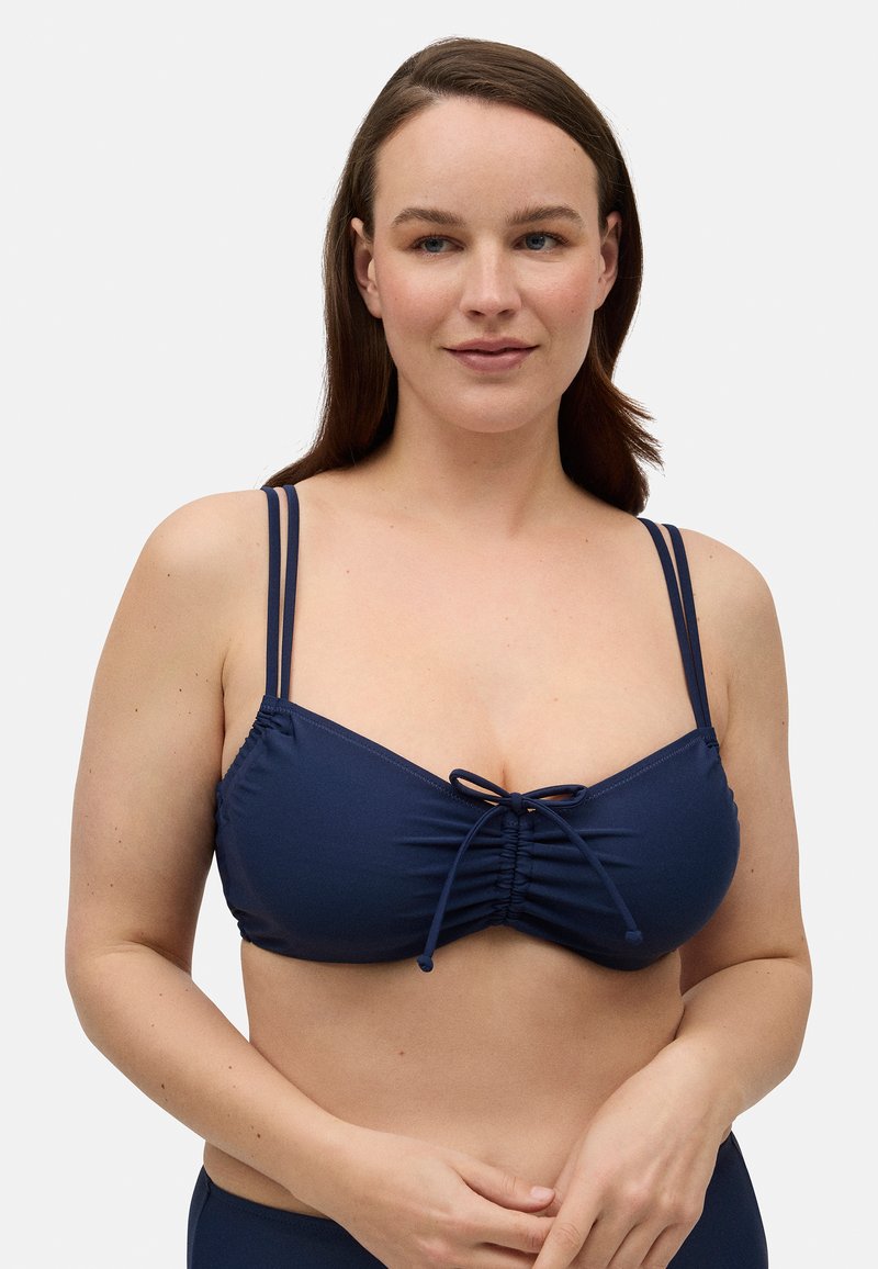 Top de bikini azul marino con tejido fruncido, ajuste regulable en el centro y dos tirantes delgados a cada lado. Textura suave y diseño ajustado.