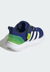 Navy blue athletic shoe with white side stripes, green translucent heel and strap, textured fabric, and white sole.