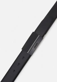 Cinturón de cuero negro con una textura suave, una hebilla metálica rectangular con un acento texturizado y cinco agujeros ajustables.