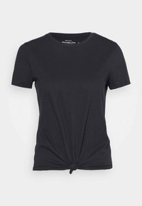 Sort kortærmet bomulds T-shirt med rund halsudskæring og en knude-detalje foran i kanten.