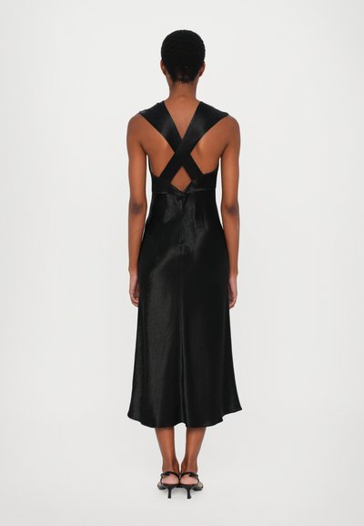 Svart satin klänning med en flödande silhuett, med korskorsade straps i ryggen och en jämn textur. Kantlinjen faller nedanför knäet.