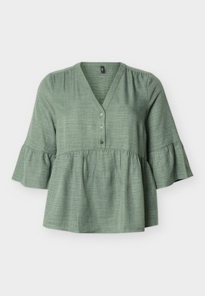 Zöld texturált anyagból készült blúz V-nyakkivágással, három gombbal, ráncolt derékkal és fodros, háromnegyedes ujjakkal, fehér háttéren.