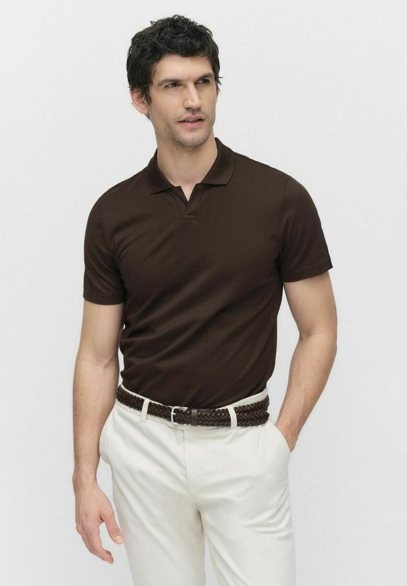 Bruine polo shirt van zachte stof, met een kraag en korte mouwen, gecombineerd met witte broeken en een gevlochten bruine riem.