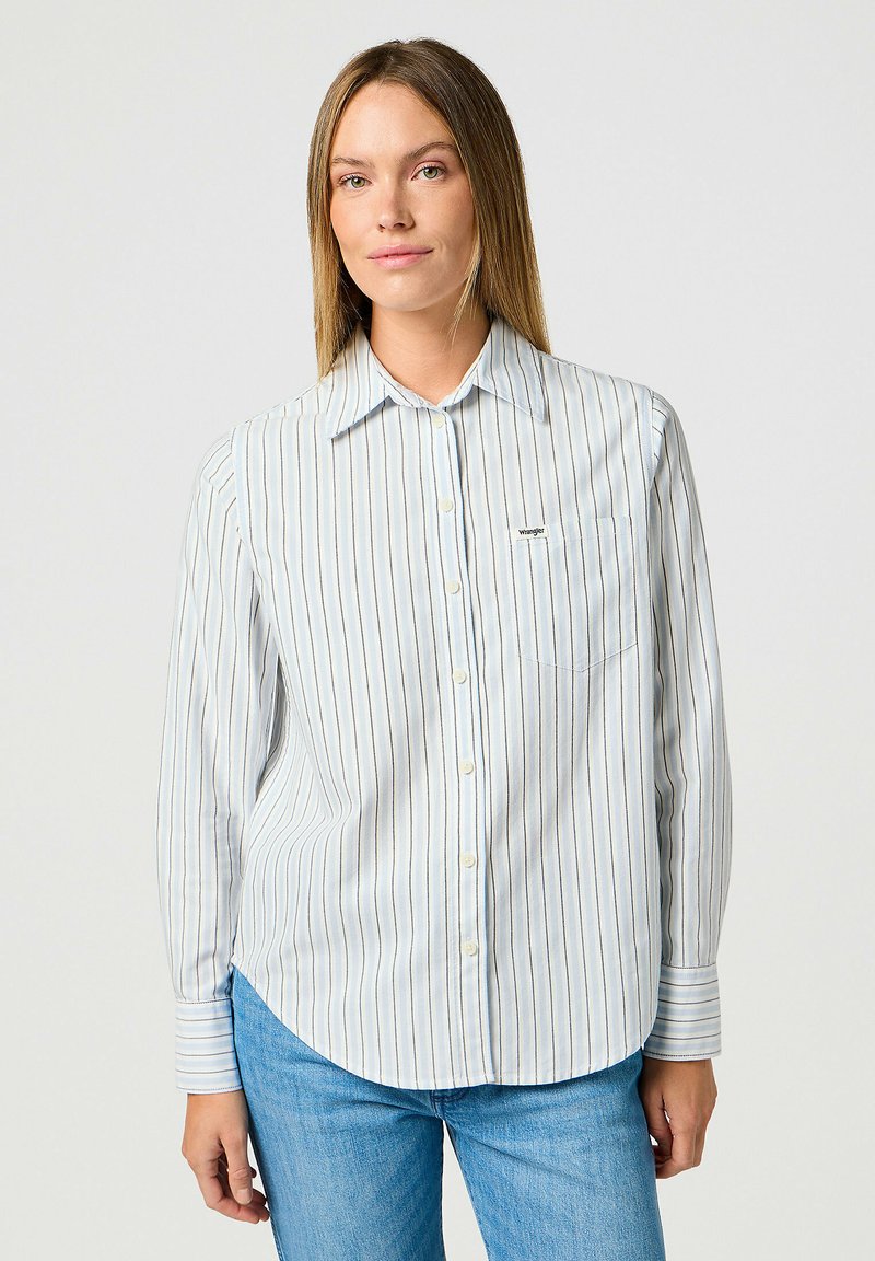 Camisa de manga larga abotonada en azul claro con rayas verticales. Presenta un bolsillo en el pecho y un dobladillo redondeado. Tejido ligero.