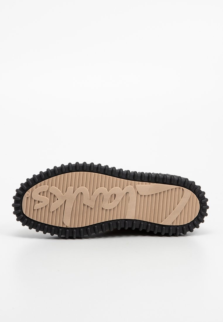 Suola della scarpa con profonda scanalatura nera e centro beige, caratterizzata da testo stilizzato in rilievo e una superficie rigata.