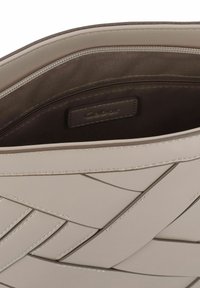 Beige Lederhandtasche mit gewobenem Design im Inneren, ausgestattet mit einem Reißverschluss und einem dunkelbraunen Innenfutter. Markenlabel im Inneren sichtbar.