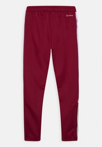 Maroon athletic pants with a textured finish, featuring a white stripe along the sides and an elastic waistband for comfort.