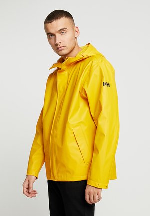 Gele waterdichte regenjas met capuchon, voorzien van een ritssluiting aan de voorkant, zijzakken en een zwart logo op de linker mouw. Gladde textuur.