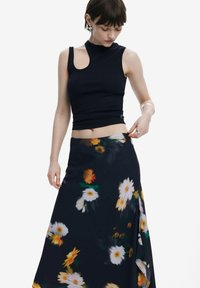 Marineblå ribbet ærmeløs top med en unik udskæring og en maksi-nederdel med blomsterdesign, der har hvide og gule blomster på en mørk baggrund.