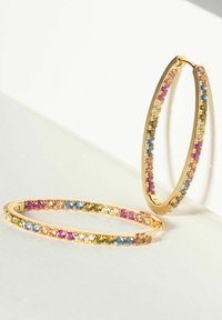 Orecchini a cerchio in oro con una fila di pietre preziose multicolori, tra cui rosa, blu e verde, incastonate in un design ovale elegante.