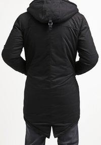 Svart, lång parka-jacka med huva, med en slät yta, quiltade axelpaneler och ett justerbart band på baksidan.