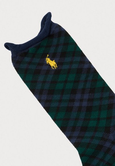 Meias até ao joelho com um padrão tartan em preto, verde e azul-marinho, com uma bainha canelada em azul-marinho contrastante e um logótipo amarelo bordado.