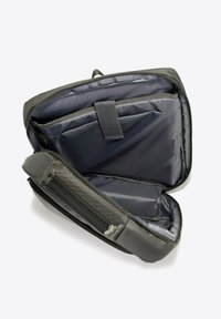 Sac à dos gris avec un extérieur texturé, comprenant de multiples compartiments et une doublure intérieure lisse. Ouvert pour montrer les poches d'organisation.