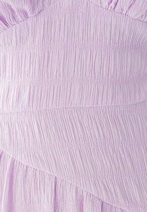 Gaiši lavandas audums ar vertikālām un horizontālām kroku tekstūrām. Iespējama neliela pievilkšanas spēja un radošas detaļas visā audumā.