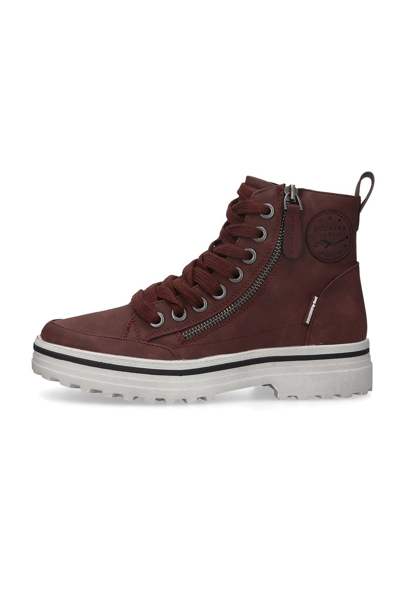Braune Leder-Hochschaftstiefel mit strukturierter Oberfläche, ausgestattet mit Metallösen, seitlichem Reißverschluss und einer weißen robusten Sohle mit schwarzem Akzent.