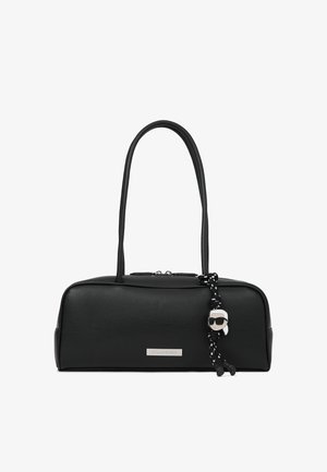 Čierna obdĺžniková kabelka s dvoma dlhými uchami, striebornou logom doskou a pleteným čierno-bielym popruhom so strapcom na malú postavičku.