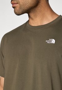 Λαδί πράσινο T-shirt με στρογγυλή λαιμόκοψη, κοντά μανίκια και μικρό λευκό κεντητό λογότυπο στο αριστερό στήθος. Μαλακό βαμβακερό ύφασμα.