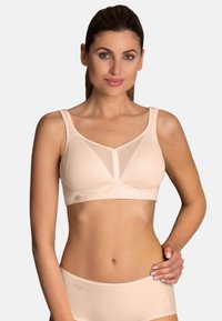Beige sports bra with a soft mesh design and smooth fabric. It features wide straps and a V-shaped neckline for support and comfort.