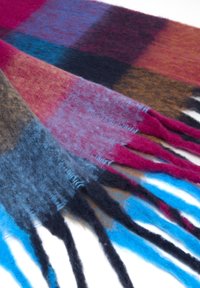 Zachte wollen sjaal met franjes aan de uiteinden in een geruit patroon van blauw, roze, paars en bruin op een witte achtergrond.