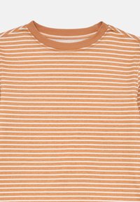 Tricou cu dungi în nuanță de portocaliu ruginiu cu dungi orizontale albe. Guler rotund cu o textură moale din bumbac. Fără grafică sau accente.