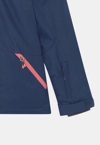 Marineblaue Jacke mit diagonalem pinken Reißverschlusstaschenärmel und verstellbarem Handgelenkband mit Klettverschluss.