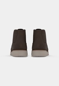 Brown leather ankle boots with a textured surface, tan rubber soles, and reinforced stitching on the sides. Smooth and durable design.