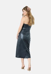 Rochie din piele neagră fără bretele, cu un corset adaptat, fustă până la genunchi, fanta laterală și o textură netedă, lucioasă.