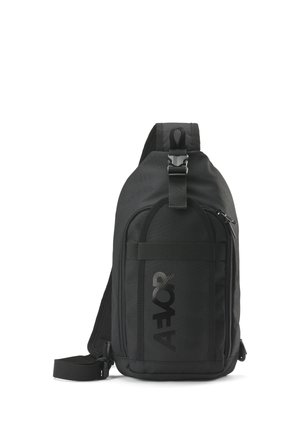 Black sling backpack with a front zipper pocket, adjustable strap, and a buckle closure on the top.