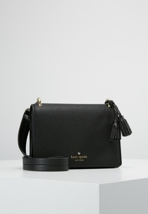 Sort læder Kate Spade crossbody-taske med guldlokale, kvastdetaljer og justerbar rem, vist på en hvid overflade.