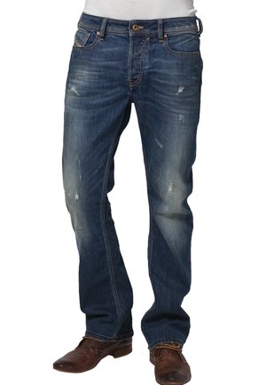 Dunkelblaue, leicht abgenutzte Herrenjeans, getragen mit braunen, strukturierten Lederschuhen und einem in die Hose gesteckten weißen Hemd.