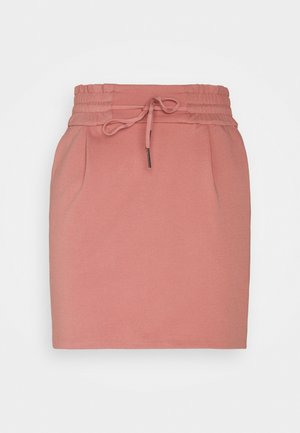 Jupe rose poudré longueur genou avec taille élastique et lien à nouer, présentant des plis discrets à l'avant et une coupe droite.