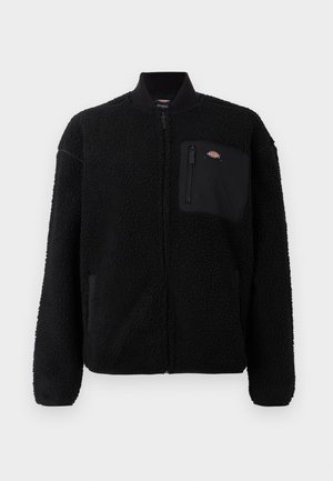 Black fleece jacket with a round collar, zippered front, and a chest pocket. Features a soft, textured surface and elastic cuffs.