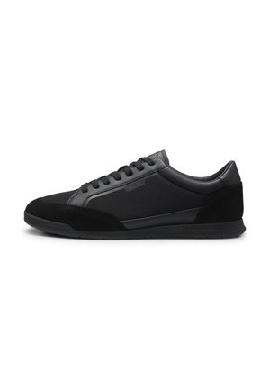 Niedriger schwarzer Sneaker mit Schnürung vorne, glatten und strukturierten Paneelen und Gummisohle, von der Seite auf weißem Hintergrund gezeigt.