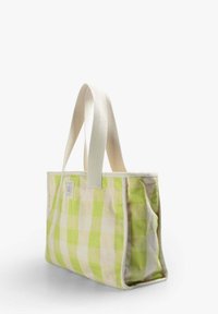 Borsa a tracolla in tessuto verde e beige a scacchi con manici in cotone bianco e un'etichetta sul davanti. Forma rettangolare con una consistenza morbida.