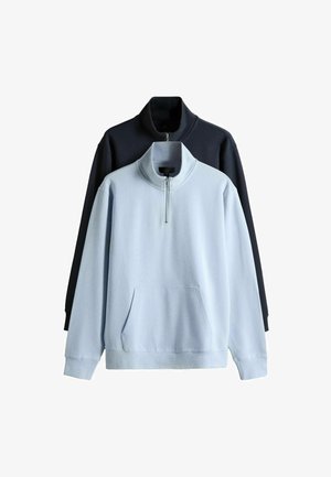 Dve fleecové mikiny s polovičným zipsom na golieri a prednými vreckami, jedna svetlomodrá vpredu a druhá čierna vzadu.