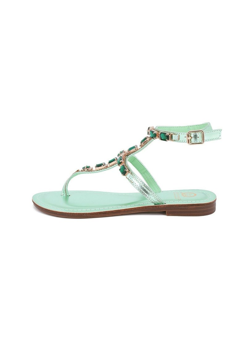 Sandal in verde menta con suola piatta, cinturini metallici e pietre decorative verdi lungo la parte superiore. Include una cinghia regolabile alla caviglia.