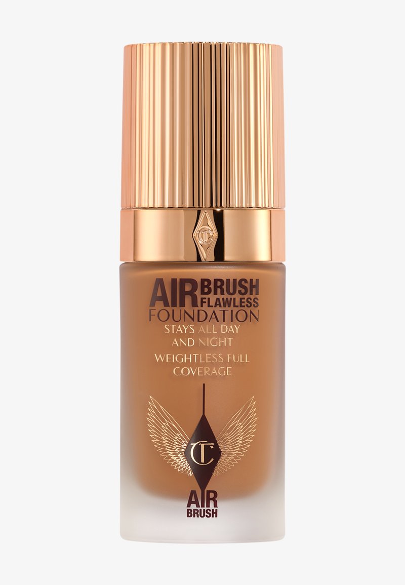 Airbrush Flawless Foundation in a brown bottle, featuring a gold ridged cap and elegant winged logo. Notable soft gradient texture.